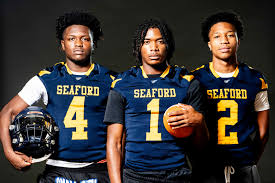 Three Seaford football players in blue jerseys.