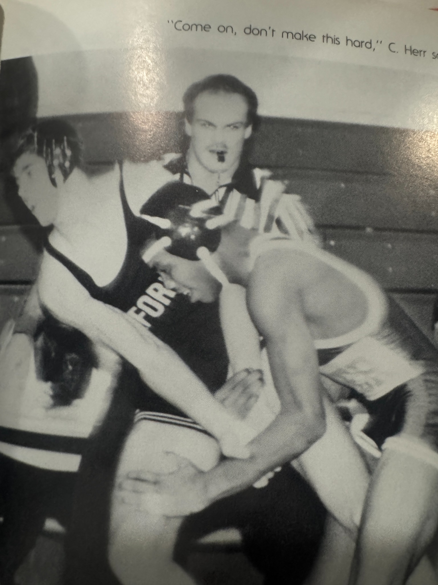 A referee watches two wrestlers during a match.